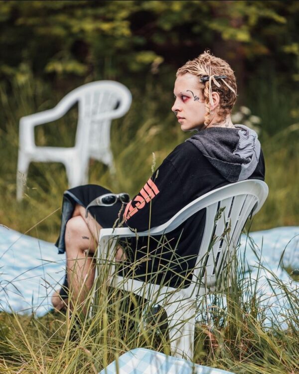 Moody goth girl sitting in a field wearing 2016 h&m Justin Bieber Purpose tour merch
