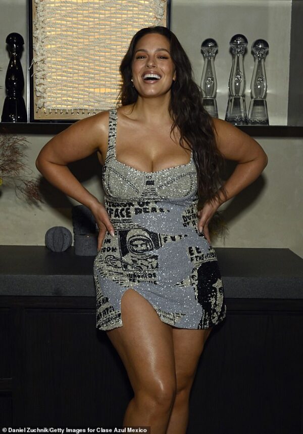 Ashley Graham looks leggy in silver newsprint mini-dress at tequila party in NYC… as her husband Justin Ervin works on film in Rwanda